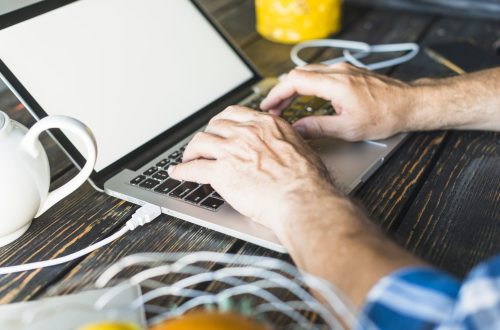 man-s-hand-typing-laptop-wooden-desk